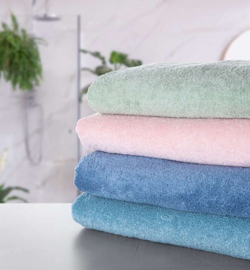 Stack of fresh towels on light grey table in bathroom